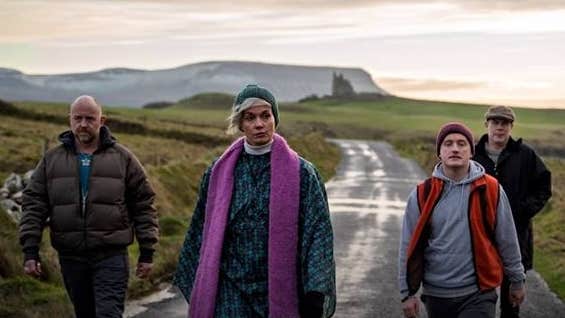 4 adults walking along a country lane on a dull day.