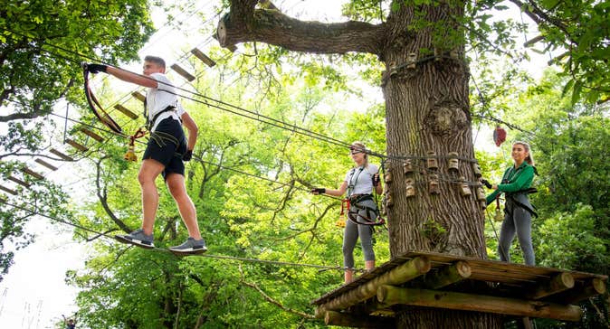 Two people ziplining through the trees with the guidance of an instructor at Lough Key Zip Line