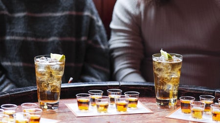 Two people sitting in front of a whiskey tasting table with a selection of glasses
