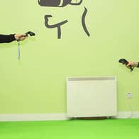 One man standing with vr equipment and one man crouching with vr equipment in a games room