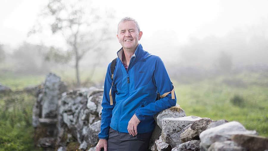 Pius Murray of Walk with Pius against a stone wall