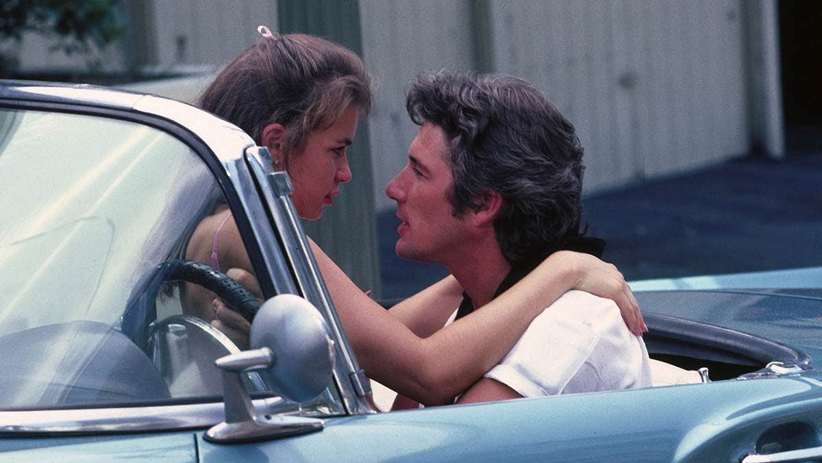 A man and a woman in a car, staring lovingly into each other's eyes.