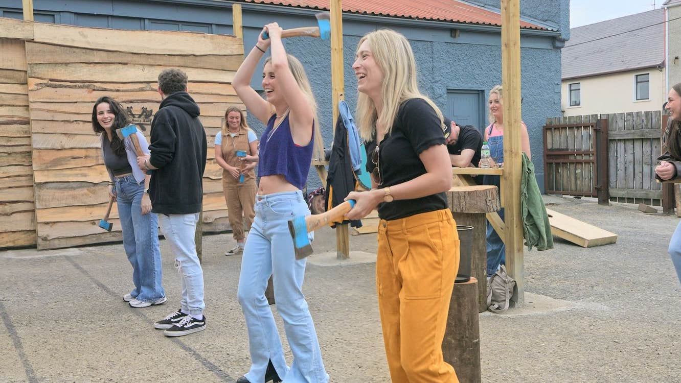 Group participating in outdoor axe throwing session with instructors