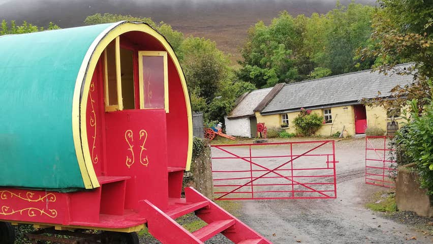 Old style horse drawn caravan by an old fashioned farmhouse