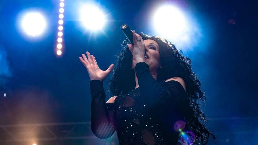 Viewed from below looking upwards at woman singing with spotlights behind.