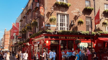 Red and black painted exterior of the temple bar pub with people walking around outside
