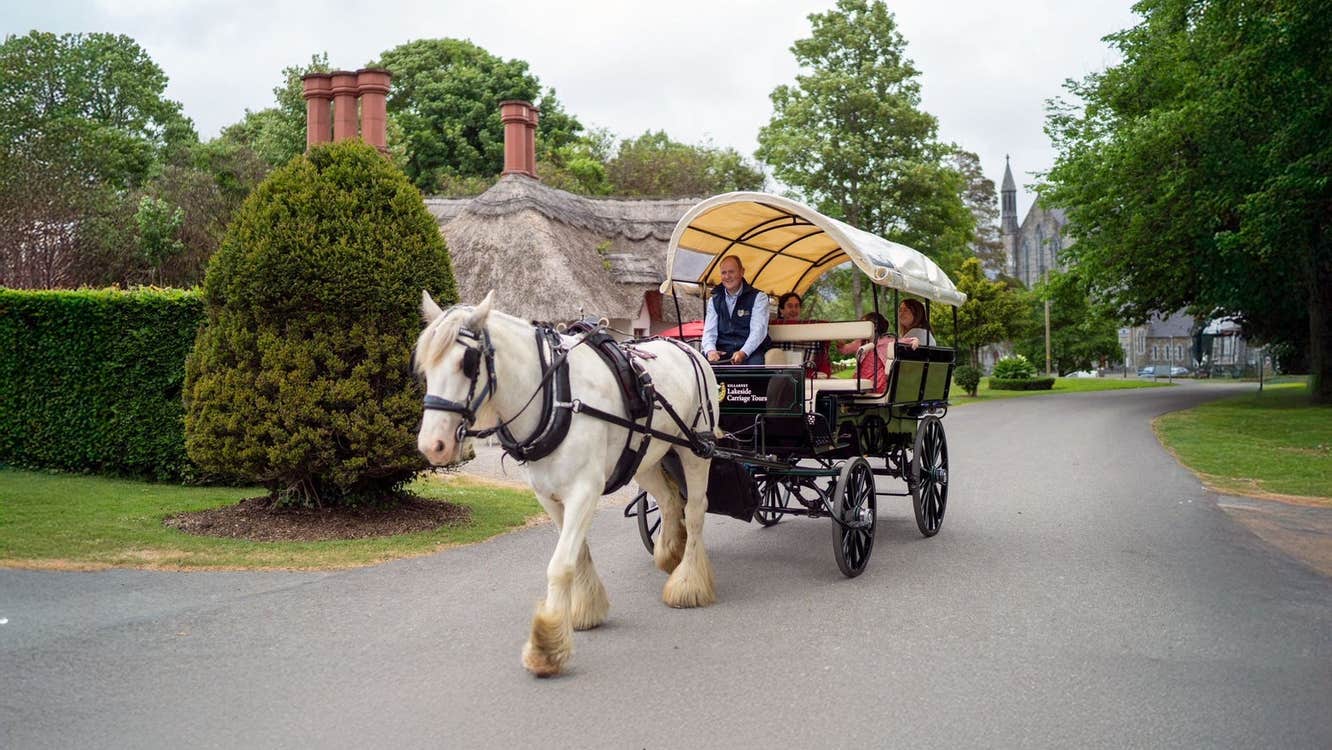 A horse drawn carriage and passengers moving down a village street