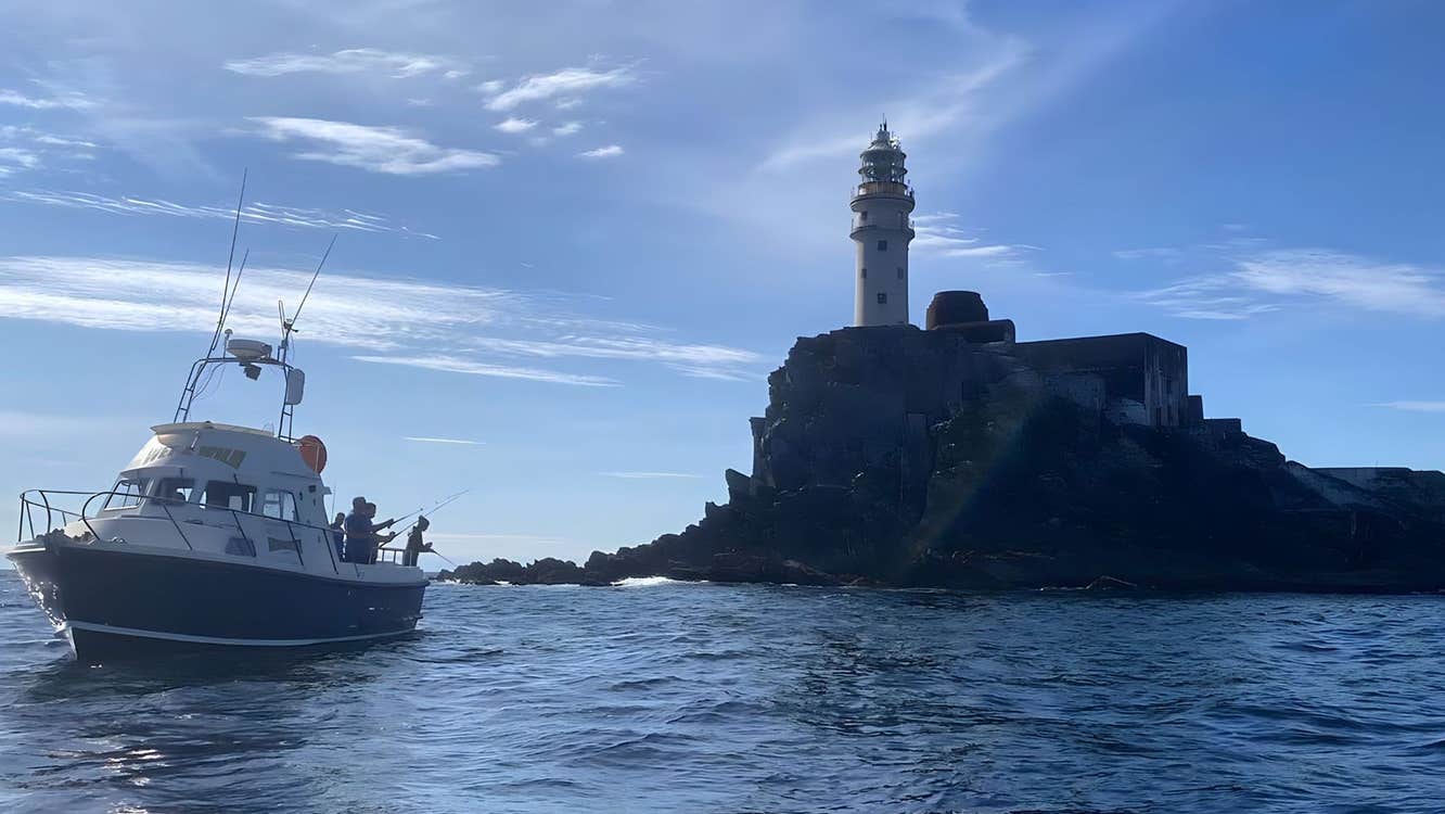 A boat with passengers sailing near a lighthouse