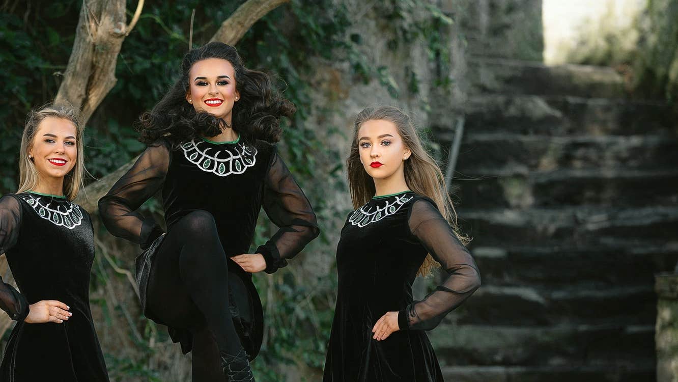 Three Irish dancers wearing Celtic dress performing with Twist of Irish