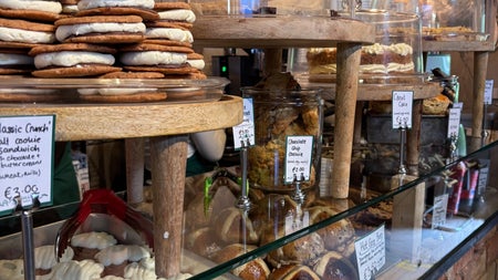 Treats and cakes on display in a glass case and red brick counter in a farm shop