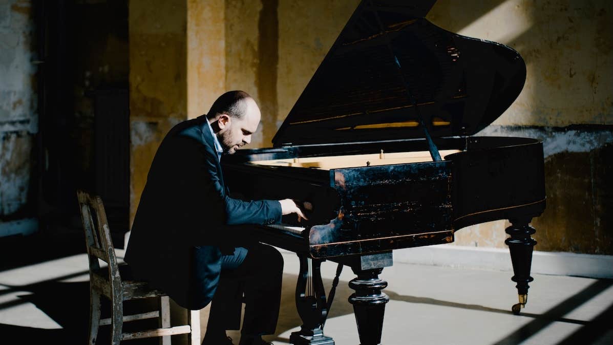 A man is seated playing a grand piano
