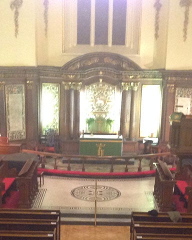 A view down from a gallery overlooking pews and an altar