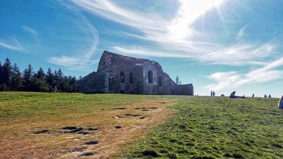 People sitting on grass and walking around the Hellfire Club in Dublin
