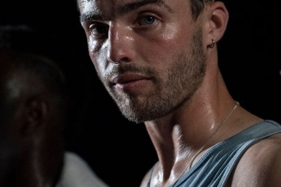 A darkly lit image of a male sweaty face