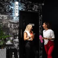 Gym members chatting against a dark wall of fitness imagery