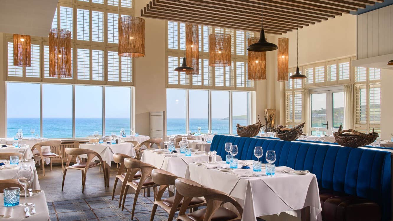 Bright coastal restaurant interior with sea views white clothed tables and blue seating