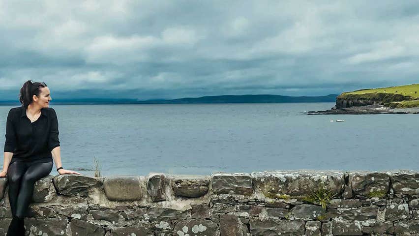 An image of the two owners sitting on a wall overlooking the harbour