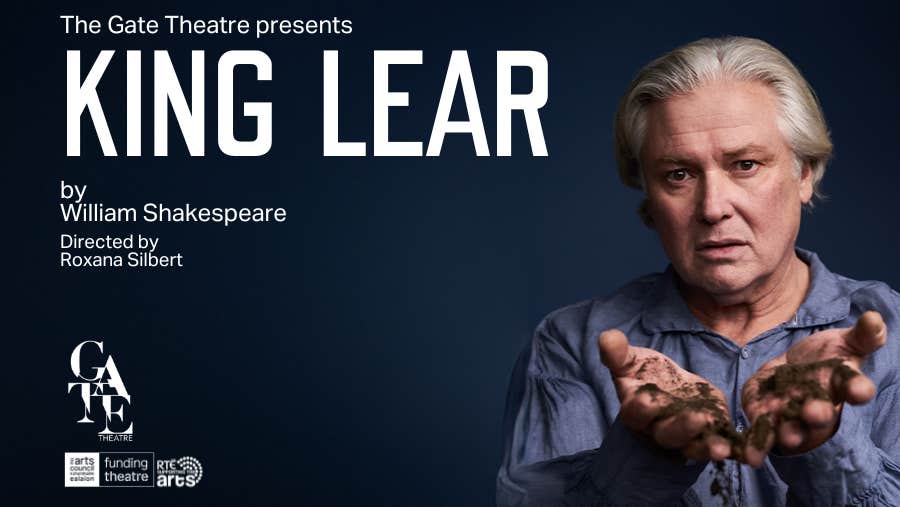 Conleth Hill appears as King Lear in the Gate Theatre. He is wearing a blue shirt, on a navy background, and holding dirt. Text reads: King Lear by William Shakespeare, directed by Roxana Silbert. Supported by the Arts Council and RTÉ.