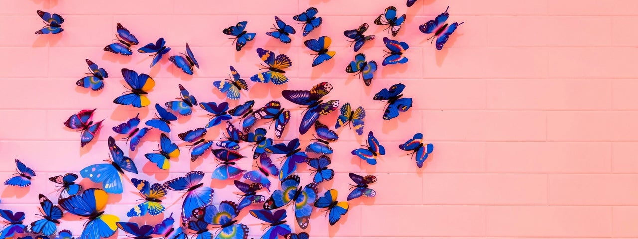Image depicting a kaleidoscope of butterflies against a pink wall