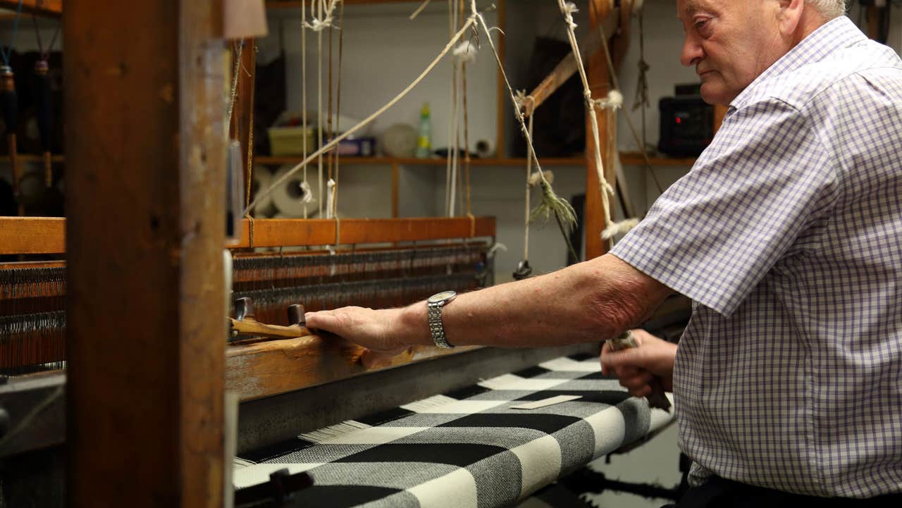 A gentleman working at a weaving loom