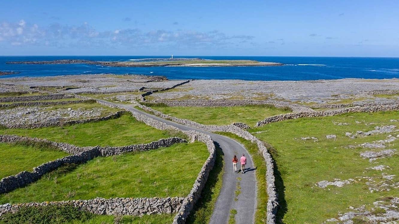 A road lined with stone walls leading to the sea