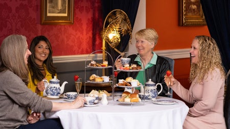 Guests enjoying afternoon tea with sandwiches pastries and hot drinks in an elegant restaurant setting