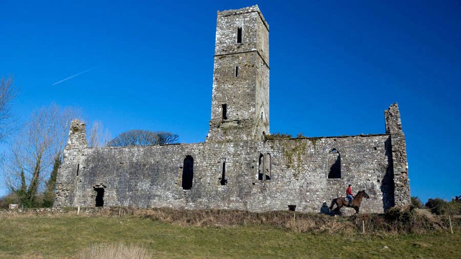 Ruins of Moor Abbey with a person on horseback near the abbey wall