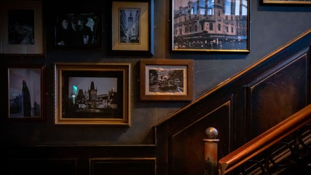 Traditional pub staircase with framed vintage photographs displayed on dark wood panelled walls