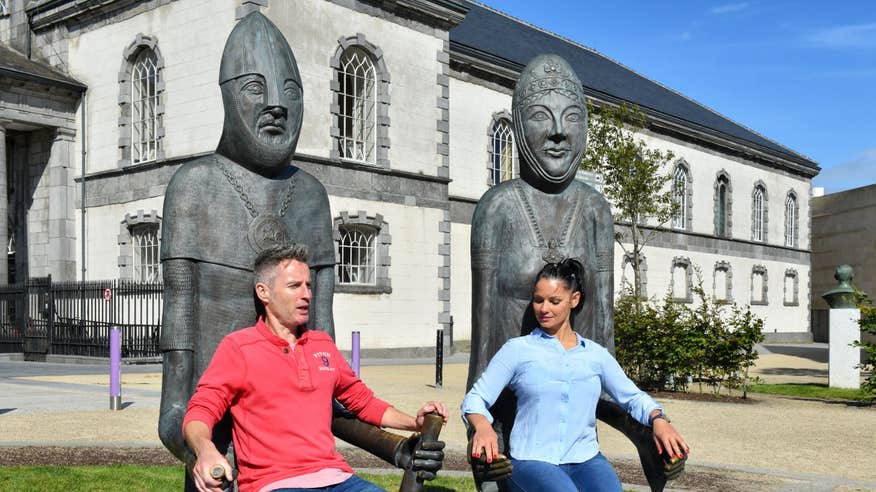 Two people sitting on stone chairs with Viking heads