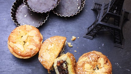 Three fruit buns with one sliced open on a table beside a model of the Eiffel Tower