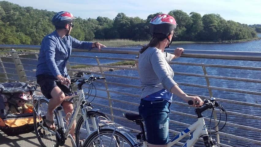 Bikes & Boards family on bikes viewing a river from a bridge