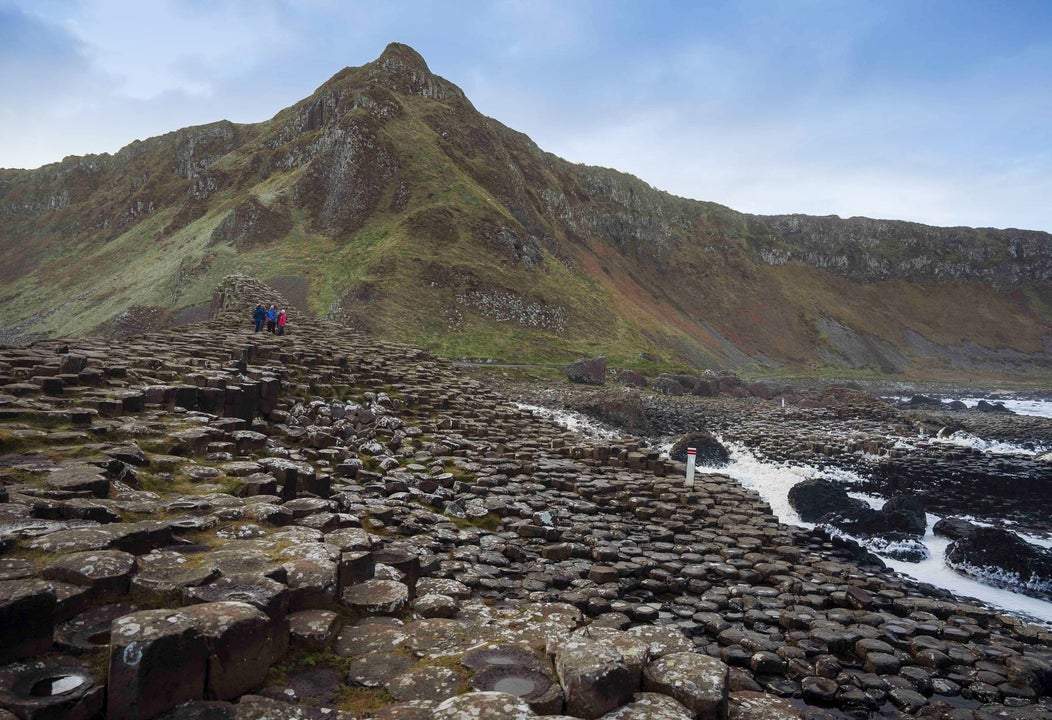 Giants causeway with people in the distance and a mountain in the background