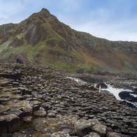Giants causeway with people in the distance and a mountain in the background