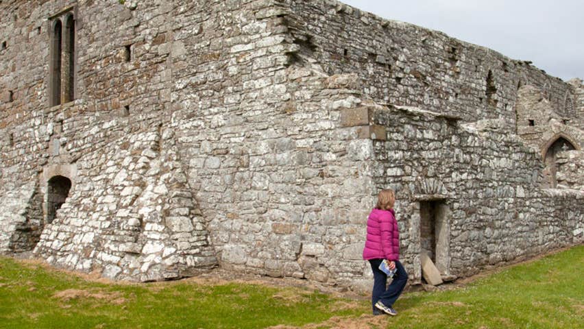 A woman walking by an ancient stone building