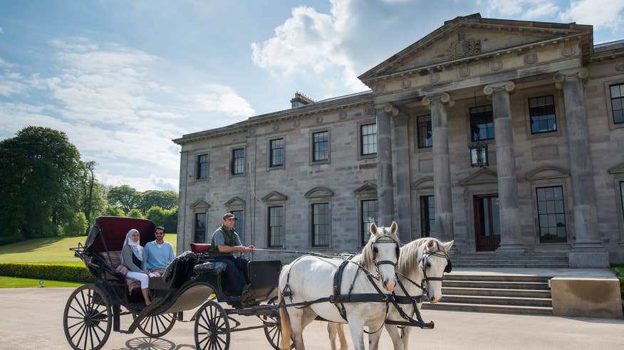A couple in a horse drawn carriage outside of Ballyfin Demesne, Co Clare