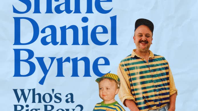 A smiling man in a stripy top standing with a young boy also in a stripy top, both with their hands in the shorts pockets.