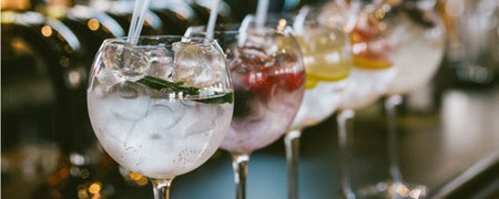 A row of gin cocktails sitting on the bar