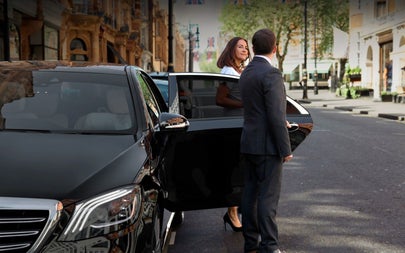 Person holding a car door as another person exits the car on a street