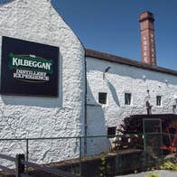 The exterior of the Kilbeggan Distillery Experience building with the old chimney in the background