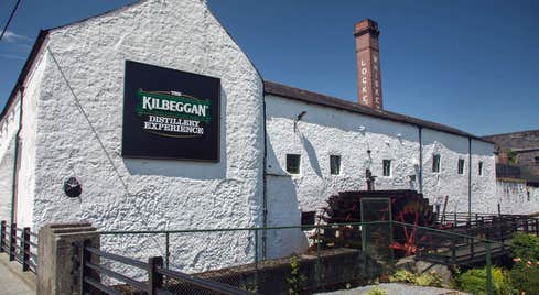 The exterior of the Kilbeggan Distillery Experience building with the old chimney in the background