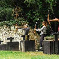 Three people practice archery with an instructor standing behind them