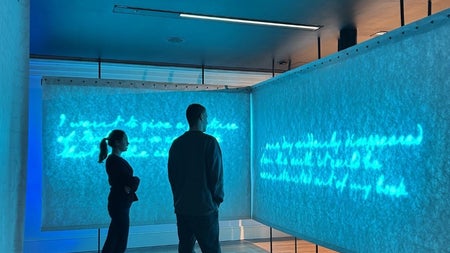 Two people standing at a visual display reading text on a screen