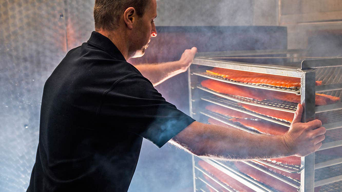 Connemara Smokehouse view of Graham looking at salmon in the smoker surrounded by wood smoke