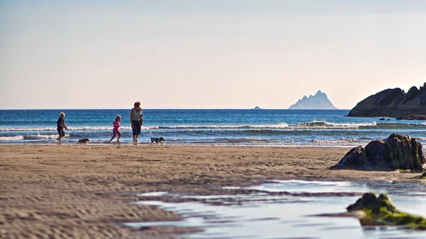 A family and dog walking on Ballinskelligs Beach, County Kerry