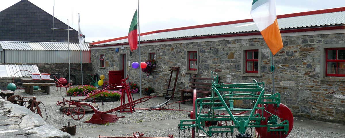 The exterior of Clew Bay Heritage Centre with old agricultural tools and machinery outside