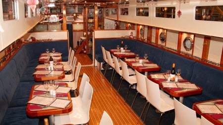 Dining area inside a canal barge with tables laid for service