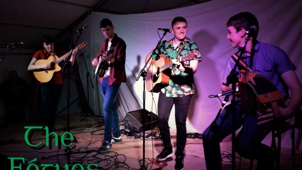 4 men on a small stage playing guitars and smiling.