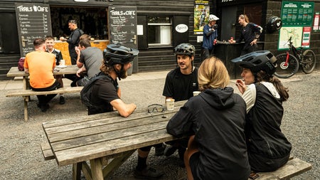 People with bicycle gear sitting on benches outside a café