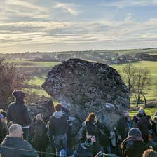 People standing around an ancient stone