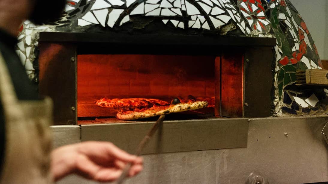 Man taking out a pizza from a pizza oven in Franciscan Well Brewery in Cork City.